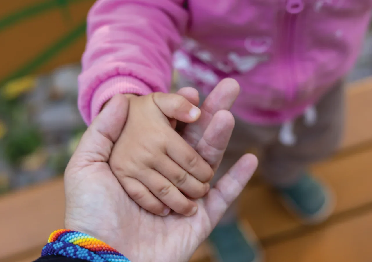 Adult and child holding hands closely