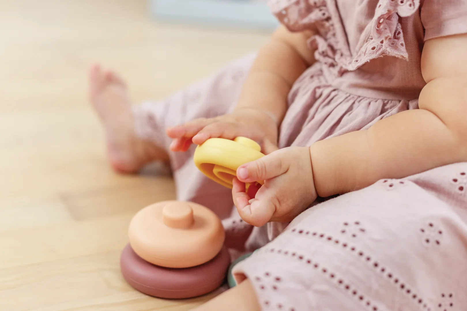 Child playing with stacking toys on floor.