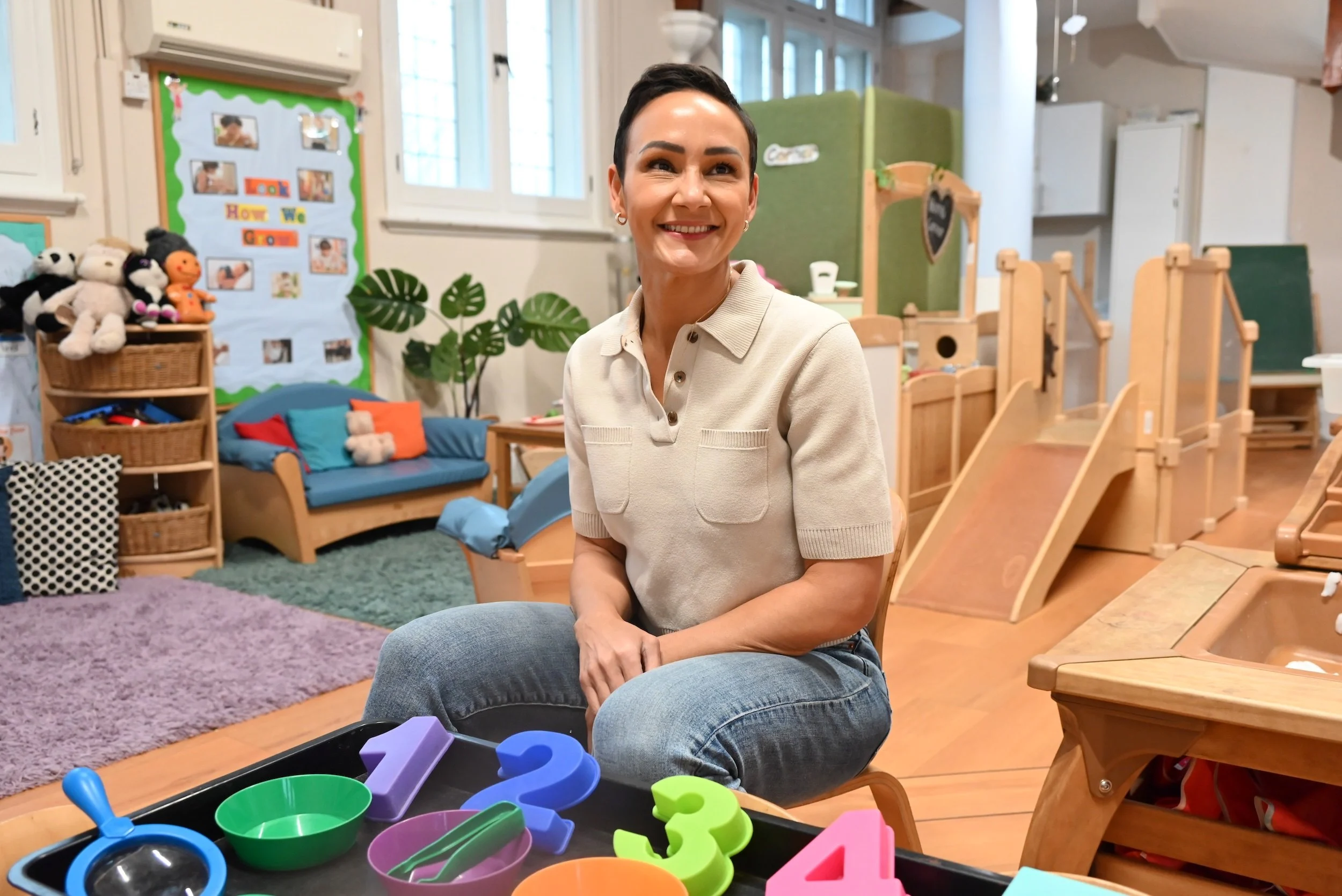 Smiling woman in nursery playroom with toys.