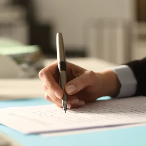 Person writing on documents with a pen