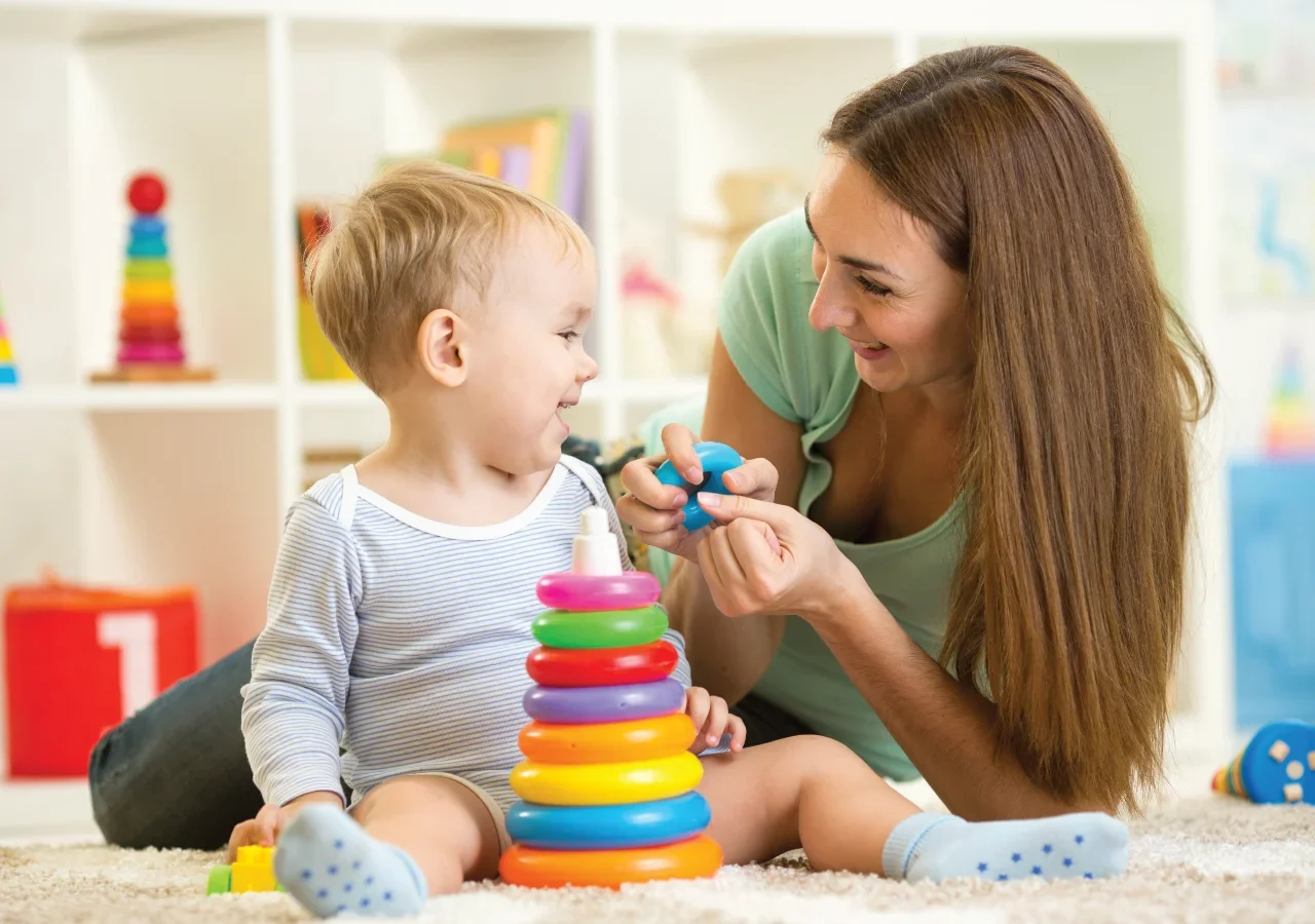 Teacher and child playing with colourful toys.
